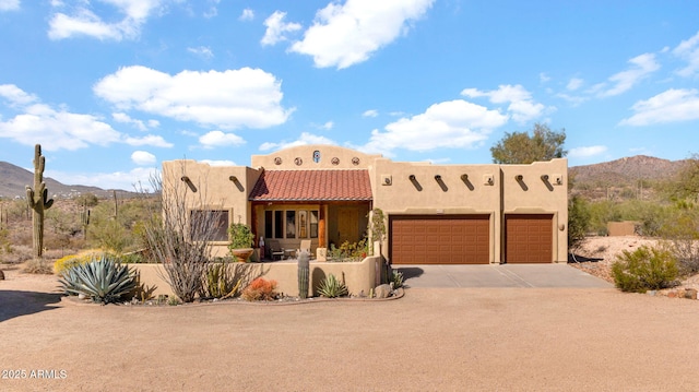 southwest-style home featuring a mountain view, stucco siding, driveway, and an attached garage