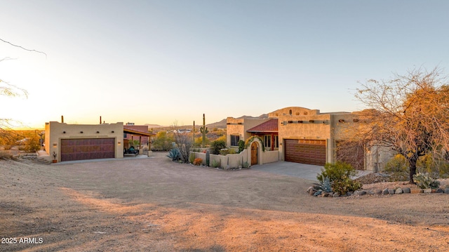 adobe home featuring stucco siding, a garage, and driveway