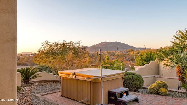 patio terrace at dusk featuring a mountain view and a hot tub