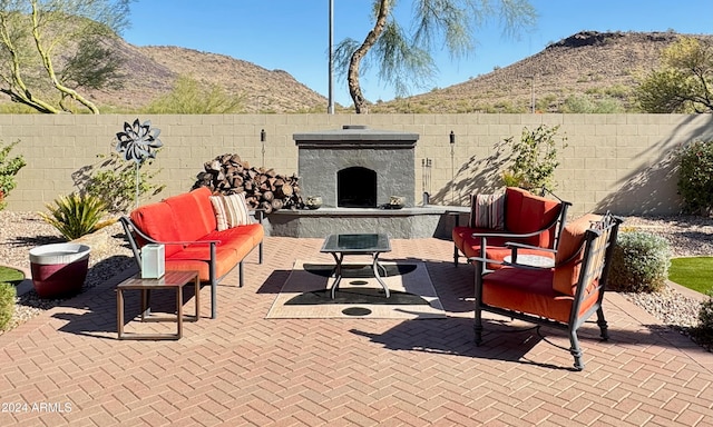 view of patio / terrace with a mountain view and an outdoor living space with a fireplace