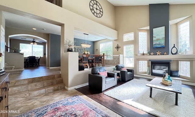 living room featuring hardwood / wood-style floors, ceiling fan with notable chandelier, and high vaulted ceiling