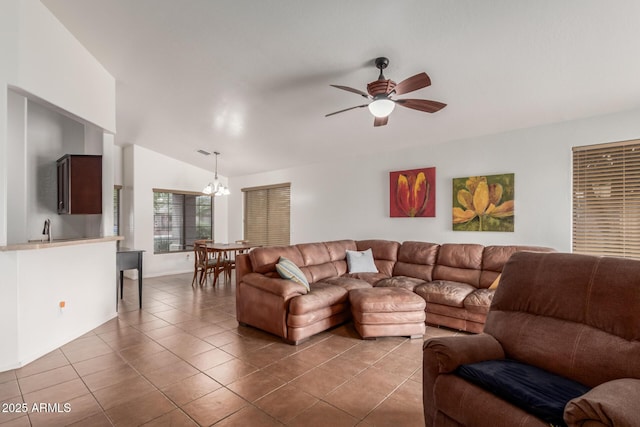 tiled living room featuring vaulted ceiling, a ceiling fan, a chandelier, a sink, and baseboards