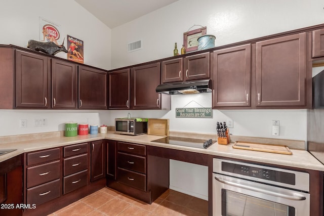 kitchen featuring under cabinet range hood, stainless steel appliances, light countertops, light tile patterned floors, and dark brown cabinetry