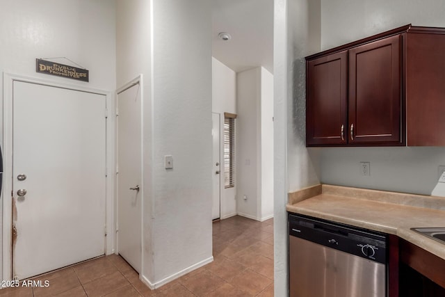 kitchen with stainless steel dishwasher, light countertops, light tile patterned floors, and dark brown cabinets