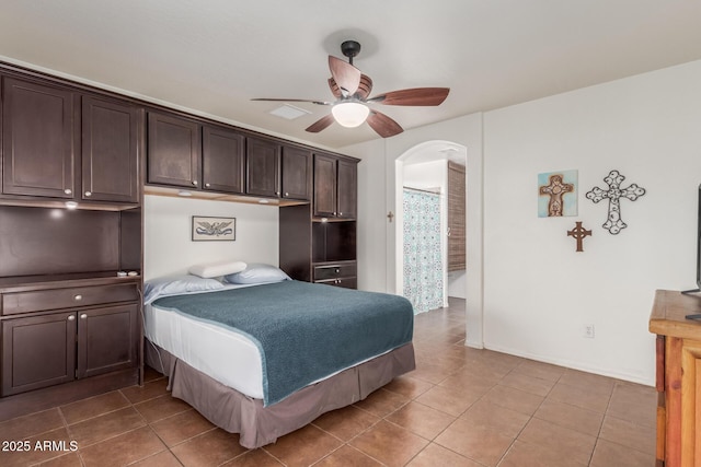 tiled bedroom featuring arched walkways and a ceiling fan