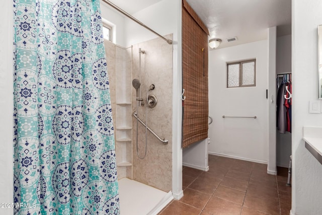 bathroom featuring a tile shower, tile patterned floors, and baseboards