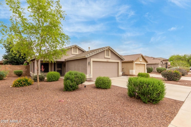 view of front of property featuring an attached garage, stucco siding, concrete driveway, fence, and a tile roof