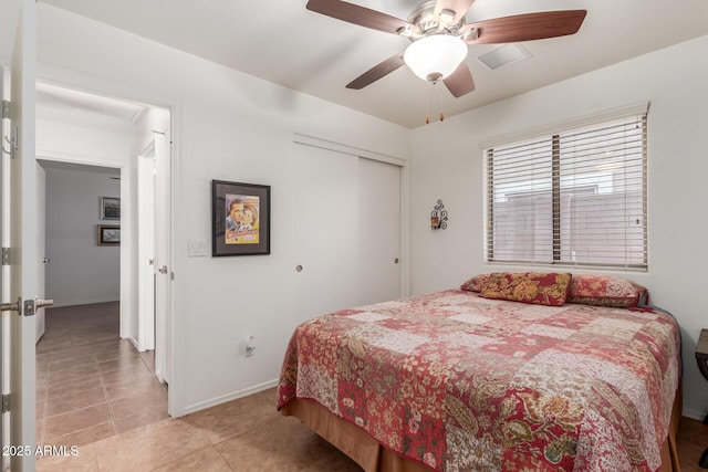 bedroom with a closet, light tile patterned floors, baseboards, and a ceiling fan