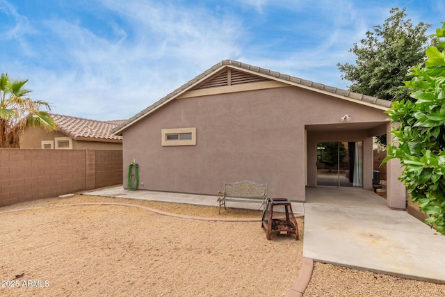 rear view of house featuring stucco siding, fence, and a patio