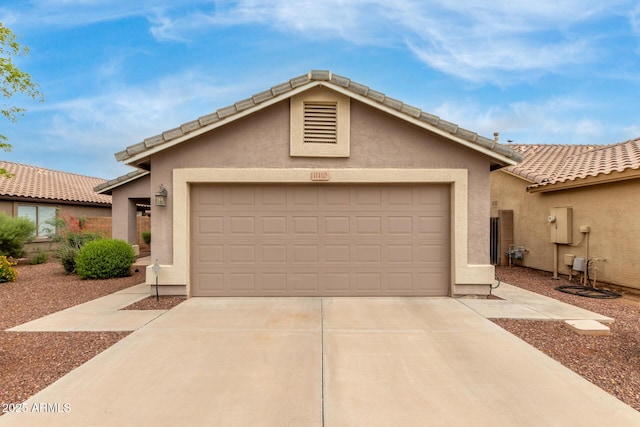 view of front of house with concrete driveway, an attached garage, stucco siding, and a tiled roof