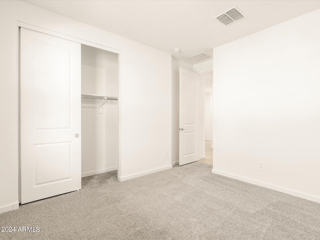 unfurnished bedroom featuring light carpet and a closet