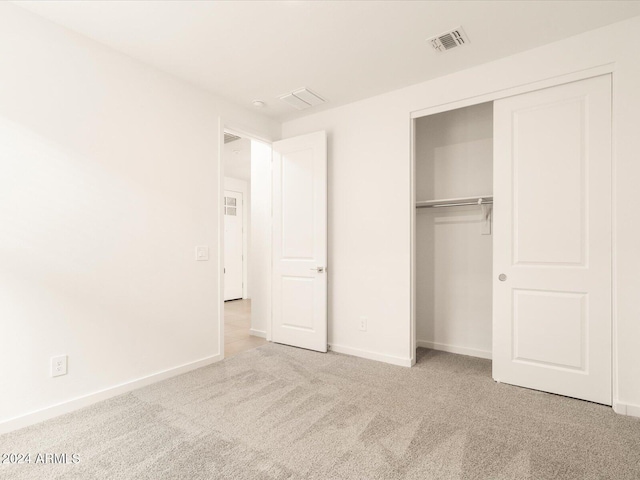 unfurnished bedroom featuring light carpet and a closet