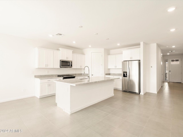 kitchen with sink, white cabinetry, a center island with sink, appliances with stainless steel finishes, and light stone countertops