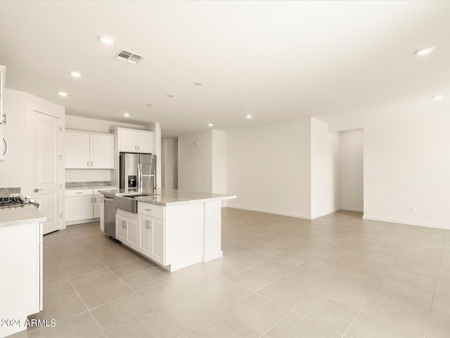 kitchen with white cabinetry, appliances with stainless steel finishes, a kitchen island with sink, and sink