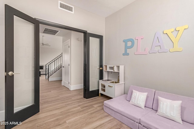 living room with light wood-type flooring, a ceiling fan, baseboards, and stairway