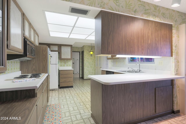 kitchen with white appliances, kitchen peninsula, sink, and a breakfast bar area