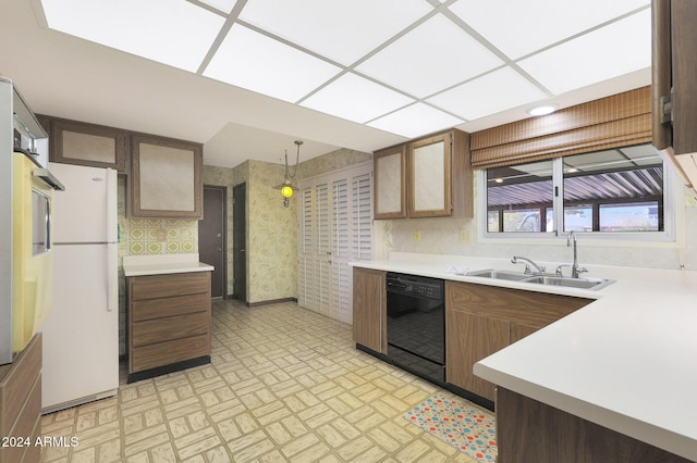 kitchen with sink, dishwasher, a drop ceiling, white refrigerator, and decorative light fixtures