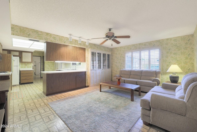 living room with ceiling fan, track lighting, and a textured ceiling