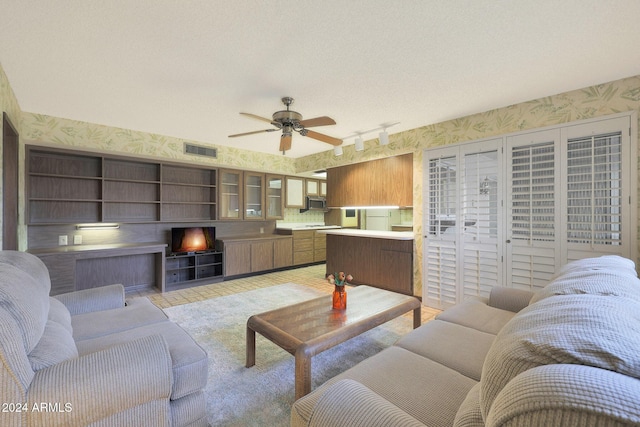 living room with ceiling fan, track lighting, and a textured ceiling