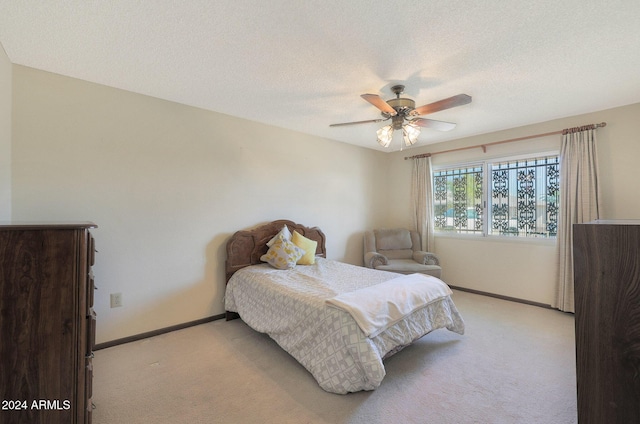 bedroom featuring ceiling fan, light carpet, and a textured ceiling