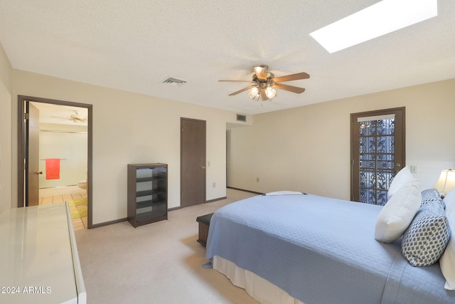 carpeted bedroom featuring connected bathroom, a skylight, ceiling fan, and a textured ceiling