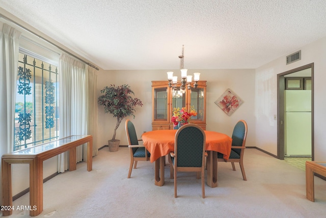 carpeted dining area with a wealth of natural light, a textured ceiling, and an inviting chandelier