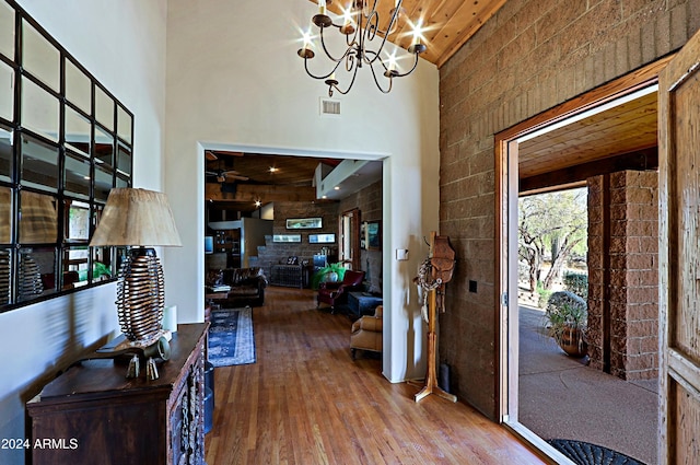 entrance foyer featuring wooden ceiling, hardwood / wood-style floors, a chandelier, and a towering ceiling