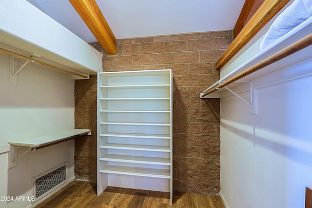 spacious closet with dark hardwood / wood-style floors and beamed ceiling