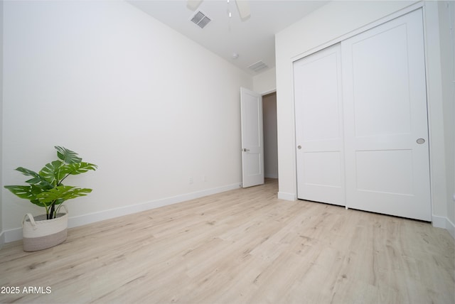 unfurnished bedroom featuring vaulted ceiling, light hardwood / wood-style flooring, a closet, and ceiling fan