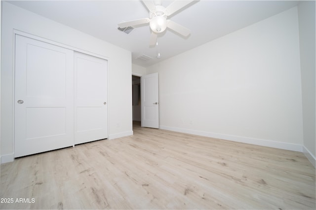 unfurnished bedroom with ceiling fan, light wood-type flooring, and a closet