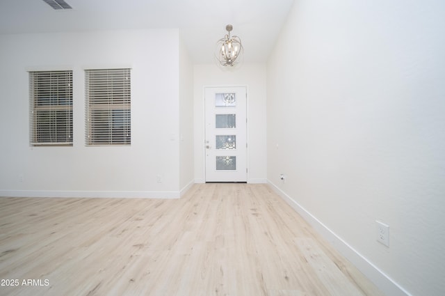 entryway featuring light wood-type flooring and an inviting chandelier