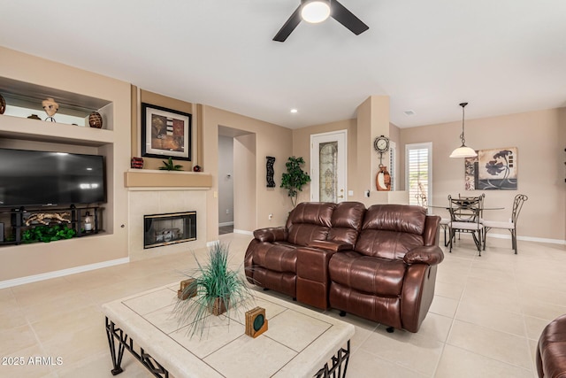 living room with light tile patterned flooring, built in features, ceiling fan, and a fireplace