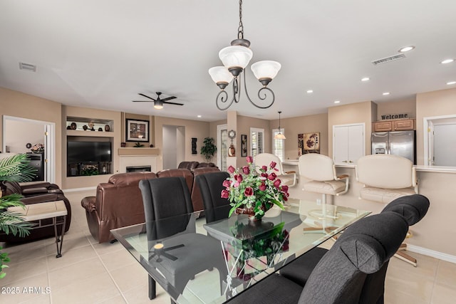 dining area featuring ceiling fan with notable chandelier, built in features, and light tile patterned floors