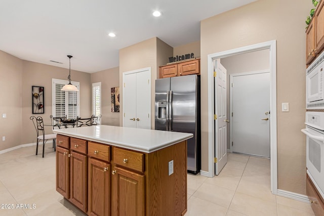 kitchen featuring hanging light fixtures, white appliances, light tile patterned floors, and a kitchen island