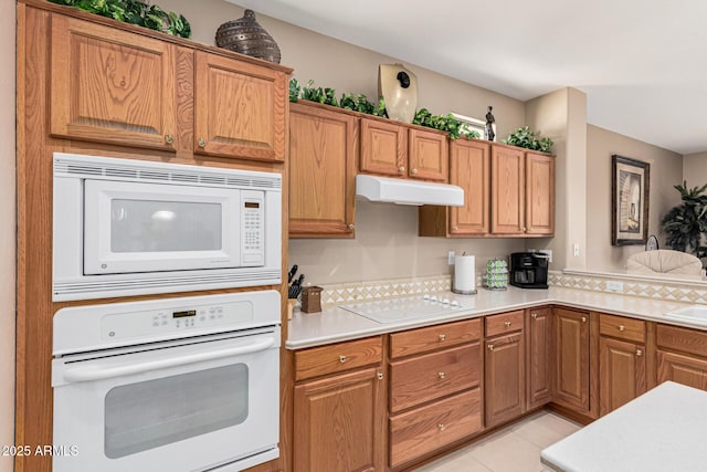 kitchen featuring tasteful backsplash, light tile patterned floors, and white appliances