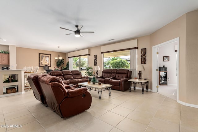 tiled living room with ceiling fan with notable chandelier