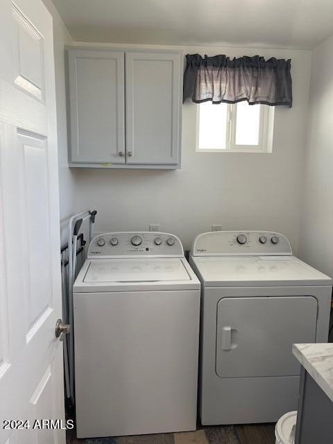 laundry room featuring washer and clothes dryer and cabinets