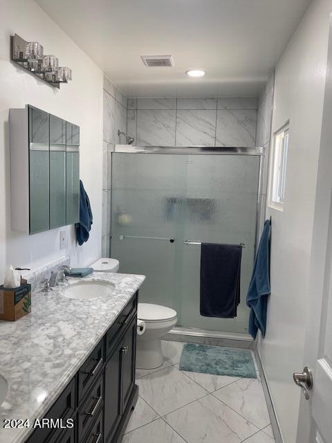 bathroom with a shower with shower door, vanity, and toilet