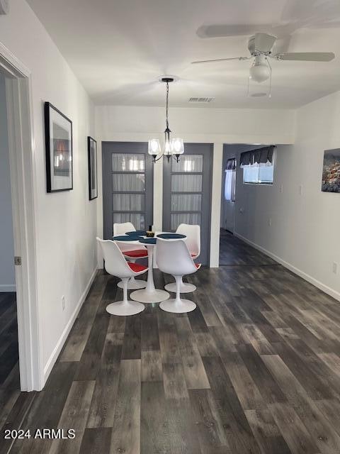 dining room with ceiling fan with notable chandelier and dark hardwood / wood-style flooring