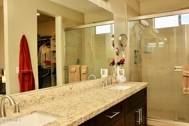 bathroom with a healthy amount of sunlight, double sink vanity, and a shower with shower door