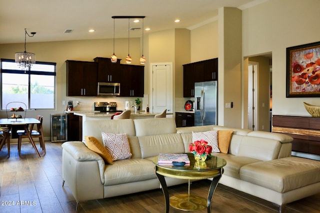 living room with high vaulted ceiling, beverage cooler, hardwood / wood-style floors, and a notable chandelier