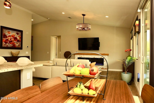 dining room featuring vaulted ceiling, dark hardwood / wood-style floors, and a fireplace