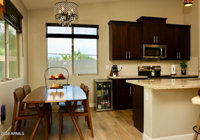 kitchen with light wood-type flooring, appliances with stainless steel finishes, beverage cooler, backsplash, and vaulted ceiling