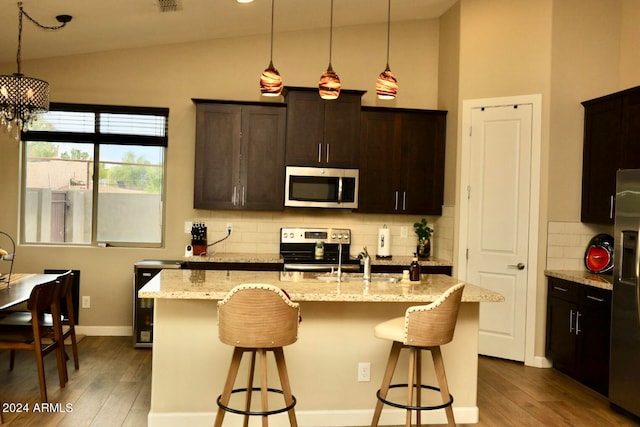 kitchen featuring backsplash, wood-type flooring, appliances with stainless steel finishes, and vaulted ceiling