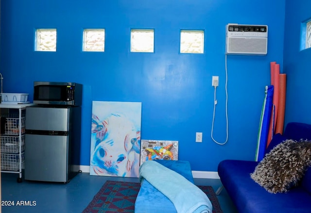 interior space with stainless steel fridge, multiple windows, and concrete flooring