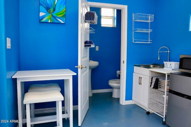 bathroom with concrete floors, toilet, and vanity