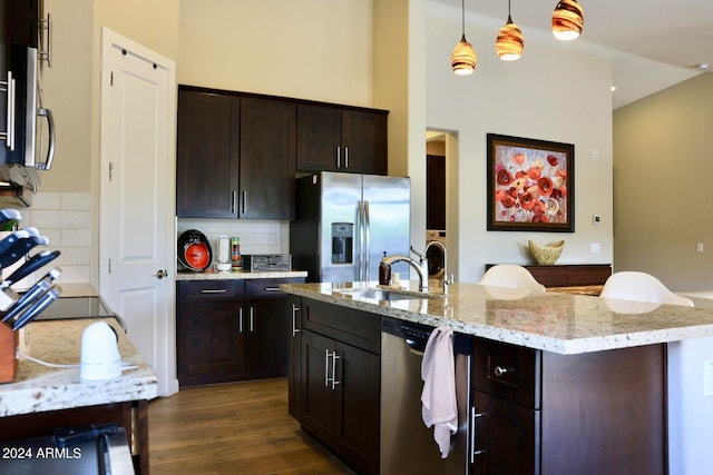 kitchen with dark hardwood / wood-style flooring, appliances with stainless steel finishes, backsplash, pendant lighting, and sink