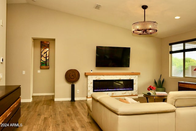 living room with a premium fireplace, vaulted ceiling, and hardwood / wood-style floors