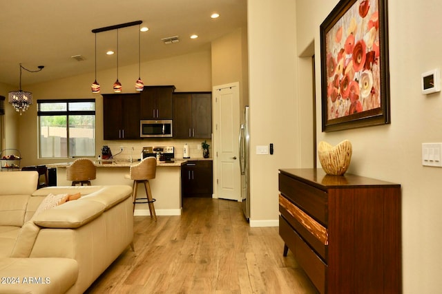 living room with high vaulted ceiling, light hardwood / wood-style flooring, and a chandelier