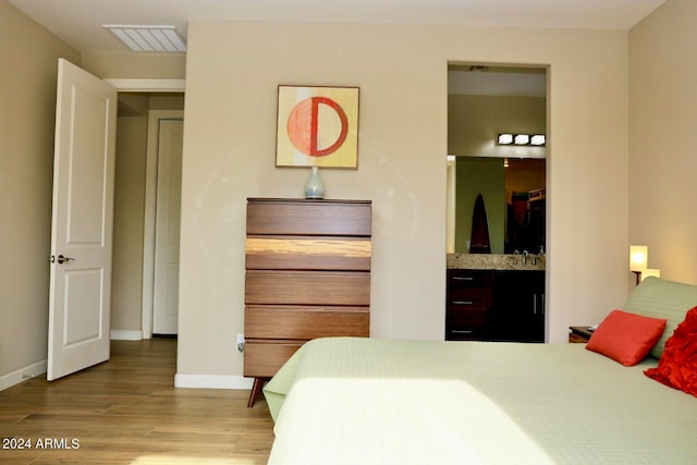 bedroom featuring ensuite bath and hardwood / wood-style flooring